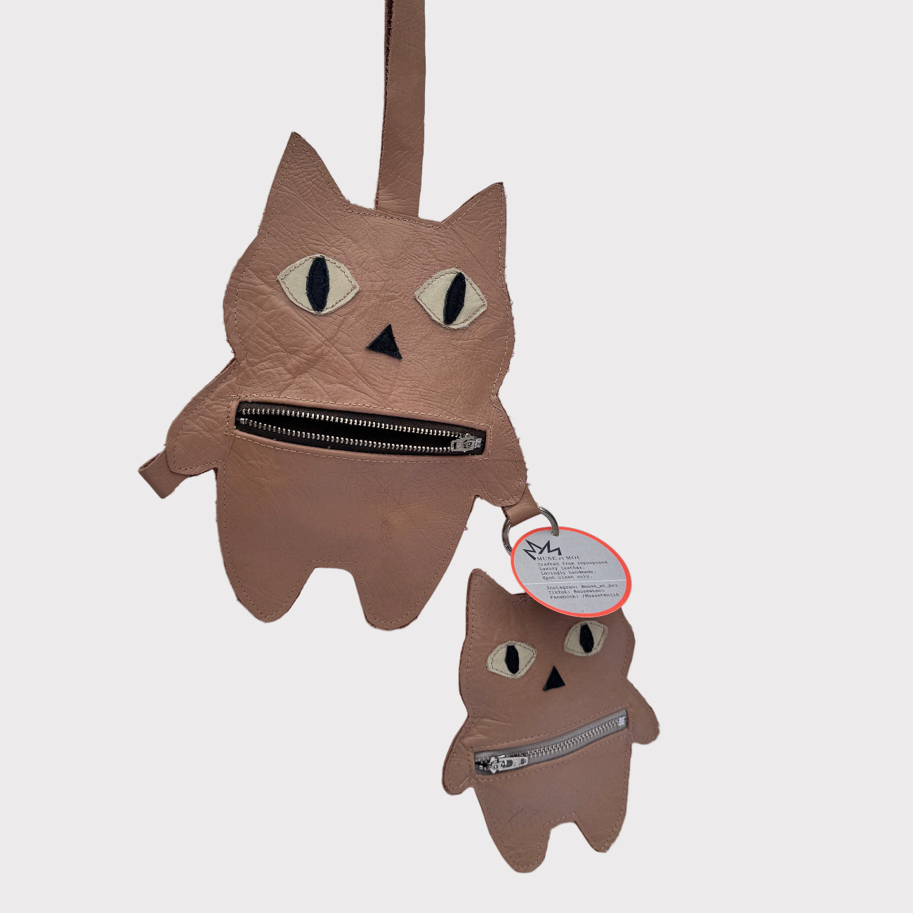 Cat-shaped oversized-bag-charms with a zipper on a white background