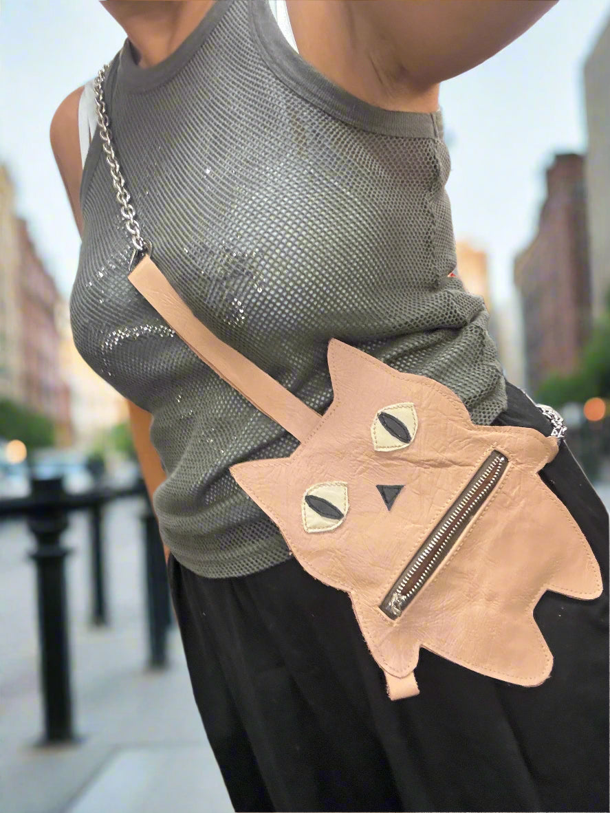 Person wearing a cat-shaped bag with a zipper on a busy street.