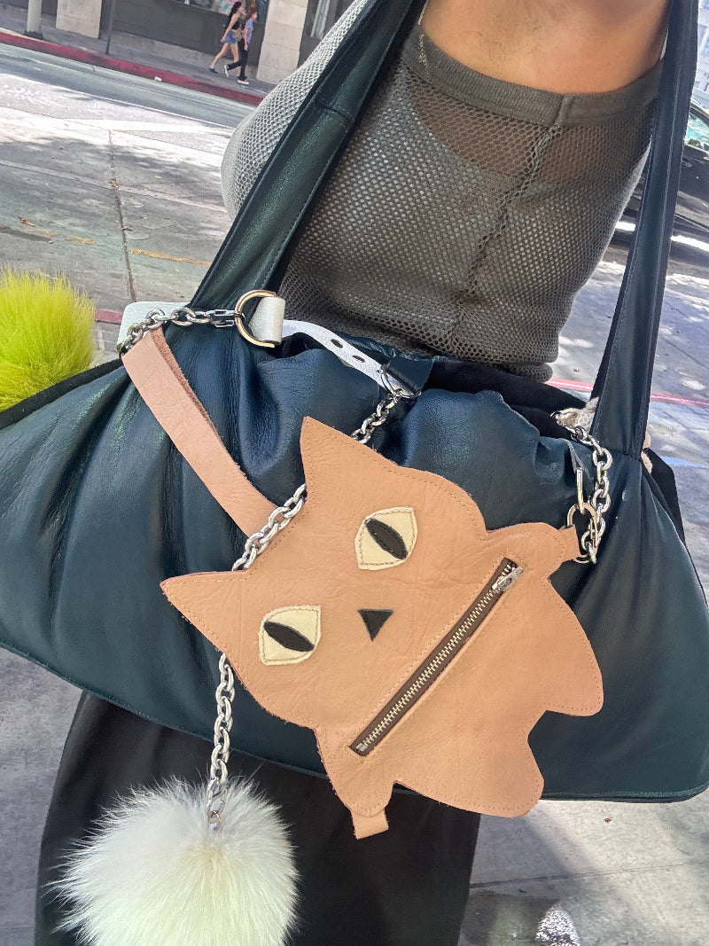 Pouch with cat design and chain strap held by a person