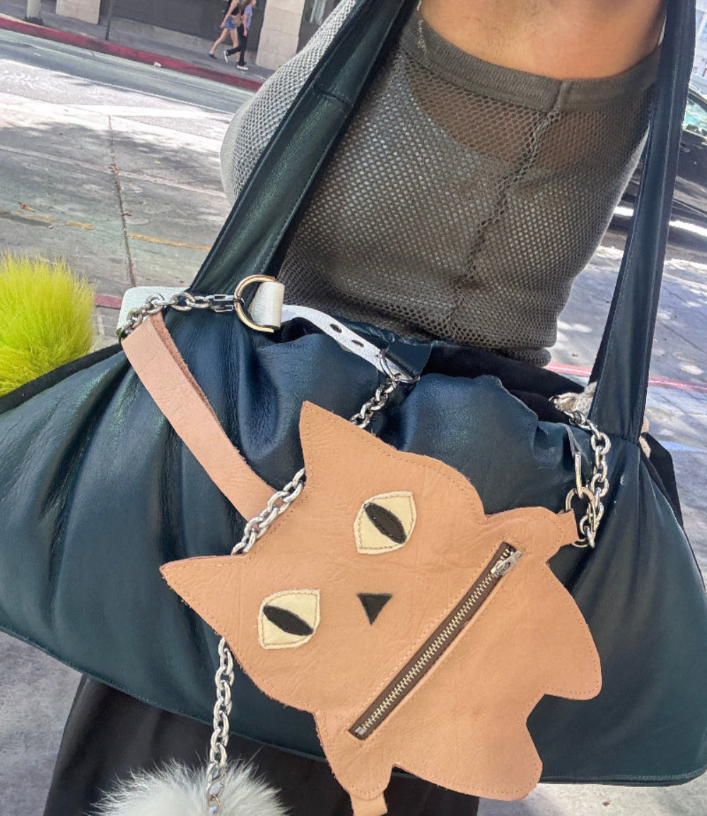 Pouch with cat design and chain strap held by a person