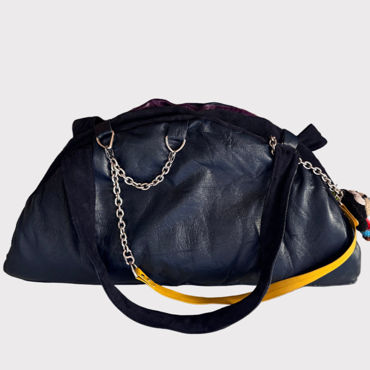 Black leather handbag with a yellow strap on a light gray background