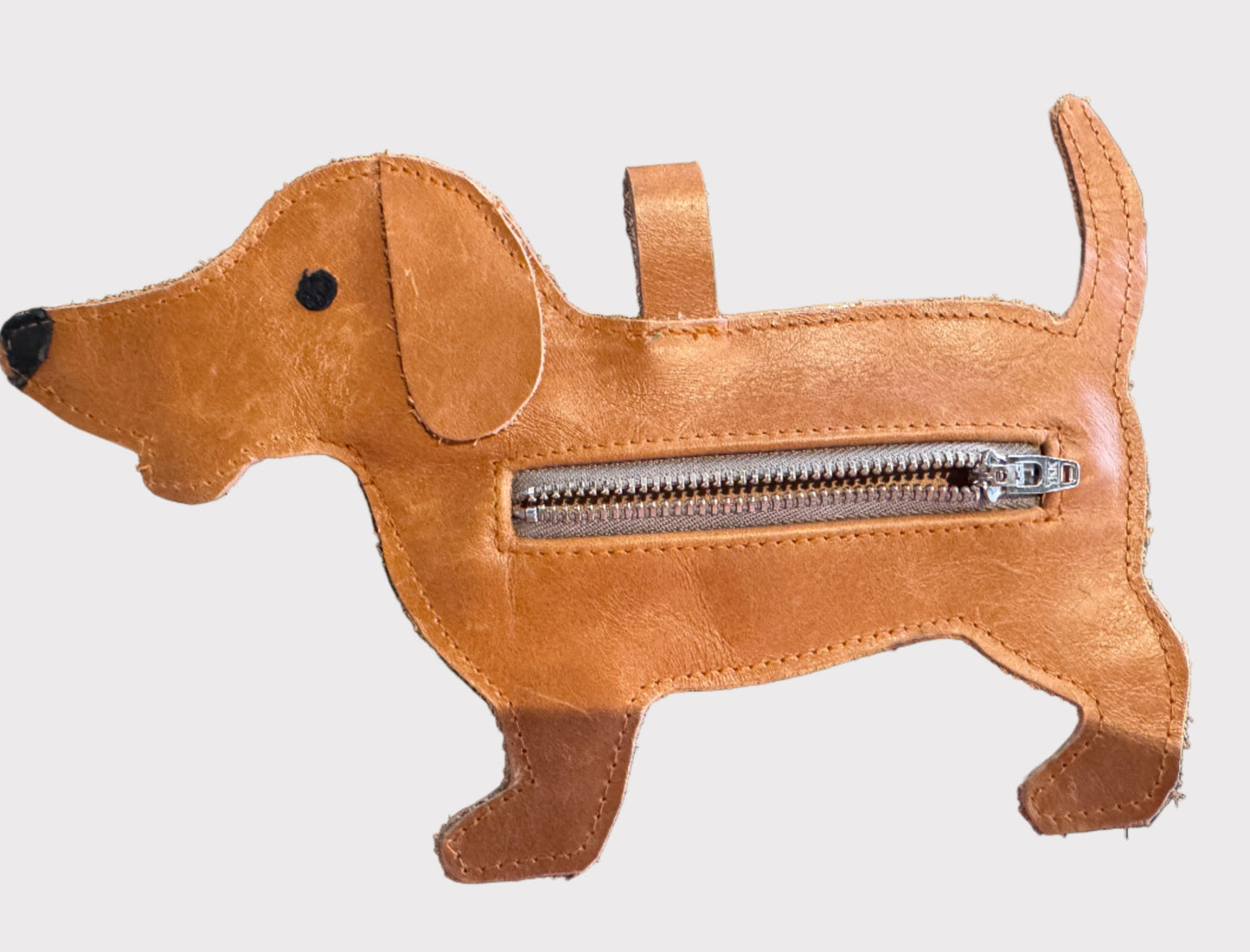 Brown dog-shaped dog-waste bag dispenser with a zipper on a white surface