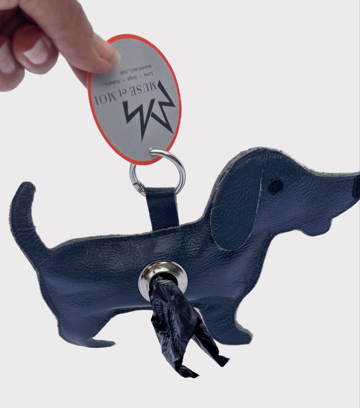 Dog-shaped dog waste bag dispenser with a tag on a light gray background