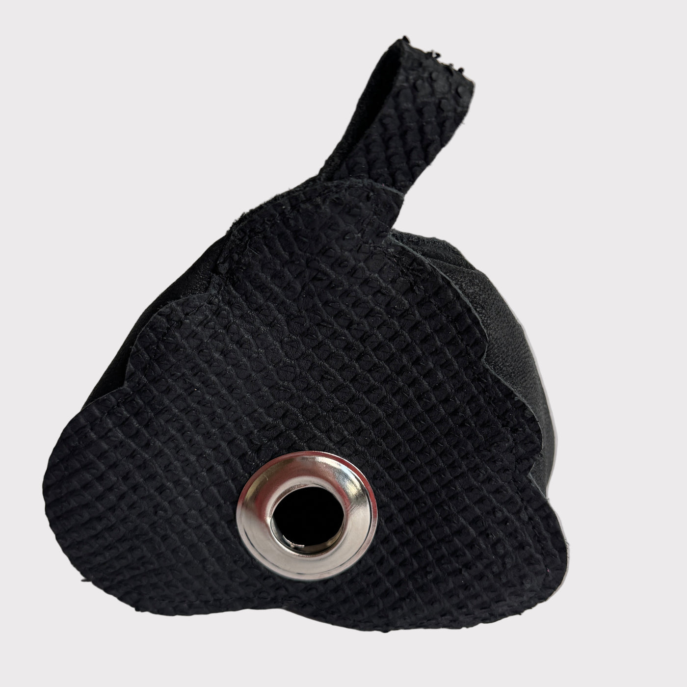 Black textured bag with a silver grommet on a light gray background