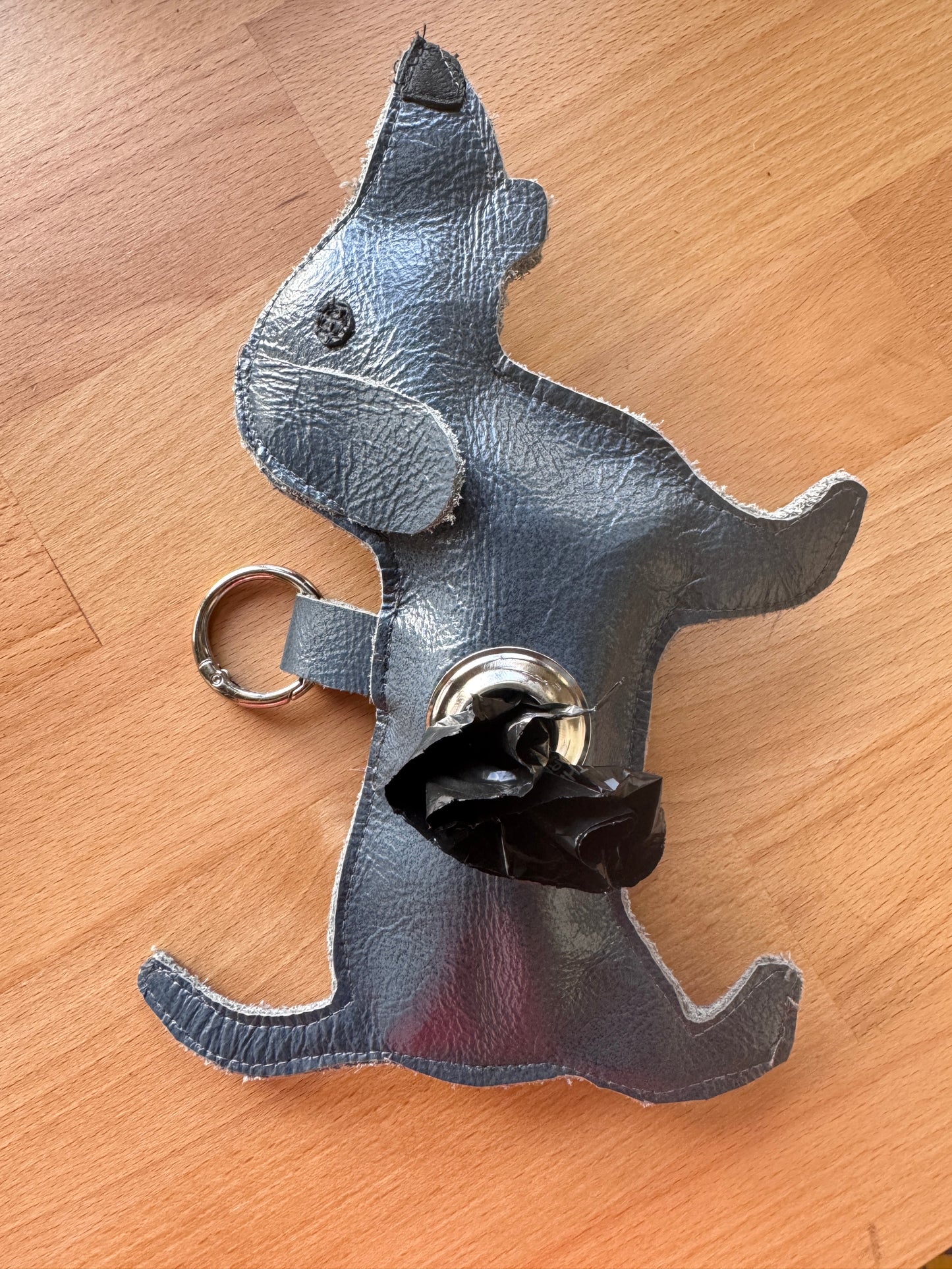 Dog-shaped keychain and dog waste bag dispenser on a wooden surface