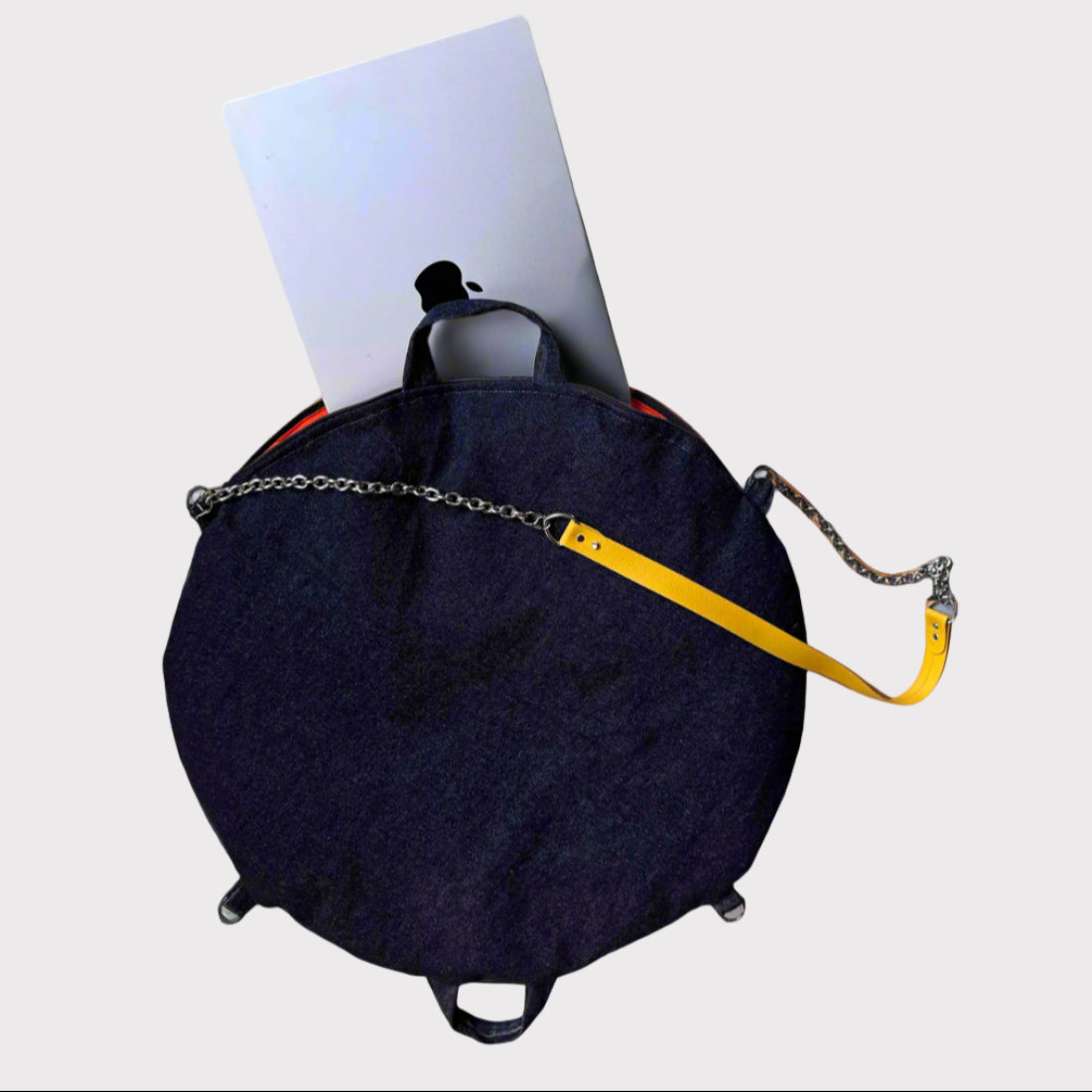 Navy bag with a yellow strap and chain on a light gray surface